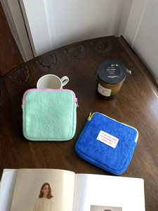 Detailed view of mint green and royal blue plush coin purses on a cozy wooden table