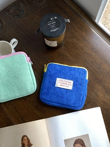 Macro detail of fluffy plush square pouches with zippers on a dark wood table
