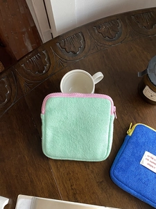 Plush towel fabric mini pouches in mint green and royal blue on a wooden desk