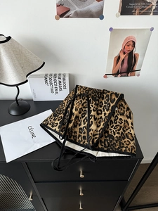 Detail of leopard print canvas tote bag with black strap in a cozy interior setting