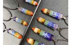 Macro detail of hexagonal 7 chakra healing crystal pendants on dark textured background