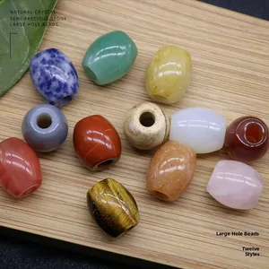 Macro shot of assorted natural gemstone barrel beads with large holes on a wooden tray