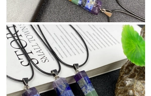 Flat lay of colorful hexagonal natural crystal pillar pendants on a white magazine