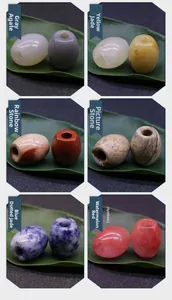 Detailed grid showing variety of 16x18mm natural stone barrel beads on green leaf