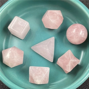 Detailed macro view of 7 pieces of rose quartz sacred geometry shapes in a teal bowl