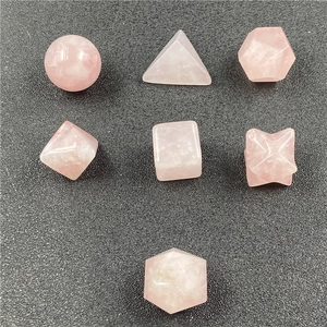Macro detail of seven rose quartz geometric faceted stones on a grey background