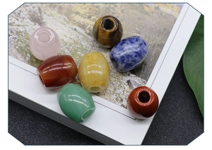 Detailed view of 7 assorted natural stone drum beads scattered on an illustrated book page