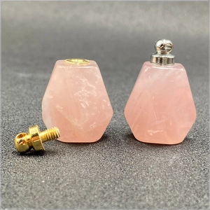 Dettaglio macro di ciondoli a bottiglia di profumo in quarzo rosa con tappi oro e argento