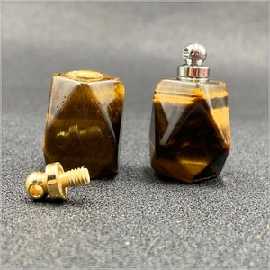 Dettaglio macro di ciondoli a boccetta di profumo in occhio di tigre con tappi oro e argento