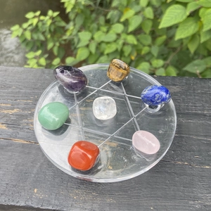 Seven chakra healing crystals set on a geometric base with natural outdoor background