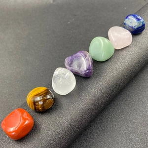 Seven chakra natural crystal tumbled stones set for meditation on black textured background