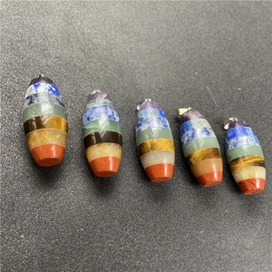 Set of seven chakra healing stone pendants with silver metal clasps on a black surface