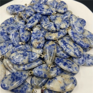 Macro shot of blue spotted stone waterdrop pendants with silver clasps in a tray