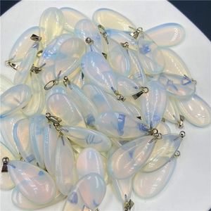 Stack of teardrop opalite crystal pendants with silver metal bails on a white tray