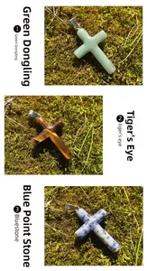 Macro of Green Aventurine Tiger's Eye and Blue Spot Stone cross pendants on moss