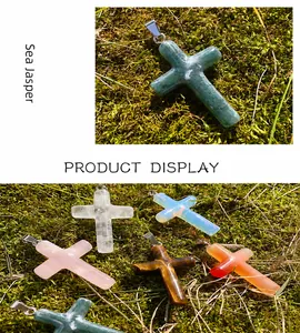 Detailed view of various cross-shaped natural gemstone pendants on mossy outdoor ground