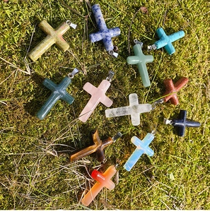 Detailed close-up of colorful natural stone cross pendants displayed on green moss background