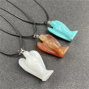 Detailed view of three carved crystal angel pendants in white, red, and turquoise tones