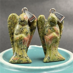 Macro view of two hand-carved unakite angel pendants with green and pink stone textures