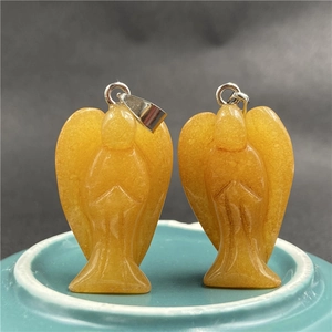 Macro shot of two orange natural crystal angel pendants with silver clasps on blue plate