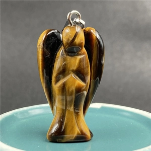 Macro shot of tiger eye stone angel pendant with polished yellow and black stripes