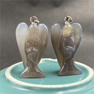 Close-up of dual angel-shaped natural agate pendants with abstract carved wing details