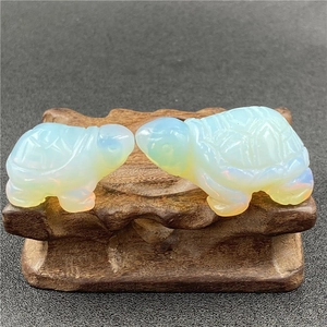 Close-up of two opalite turtle statues with shell carvings on a wooden base stand