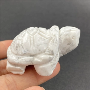 Macro detail of hand-held 2-inch carved white turquoise turtle figurine with stone texture