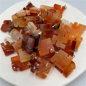 Macro shot of natural agate swastika pendants in carnelian red with silver metal clips