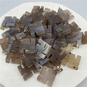 Close-up of violet crystal agate swastika pendants arranged in a white ceramic dish
