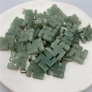 Macro view of green jade swastika pendants with metal clasps in a white tray