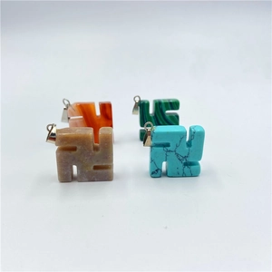 Close-up of four colorful swastika stone pendants with green, orange, and brown textures