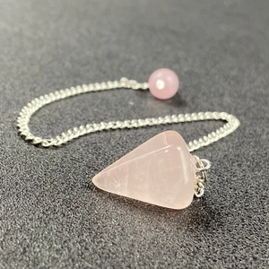 Macro shot of natural rose quartz hexagonal pendulum pendant with silver chain and bead