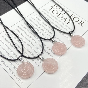 Détail de quatre pendentifs fleurs en quartz rose sculpté avec colliers en cordon noir