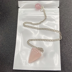 Macro detail of hexagonal rose quartz pendulum with silver chain on dark background