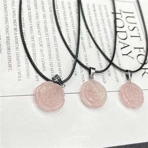 Détail des pendentifs rose en quartz rose avec pétales sculptés et cordon noir élégant