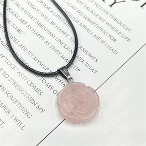Détail du pendentif en quartz rose sculpté à la main avec un cordon noir tressé
