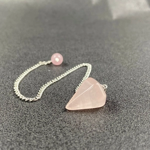 Macro detail of hexagonal rose quartz pendulum with silver chain on textured background