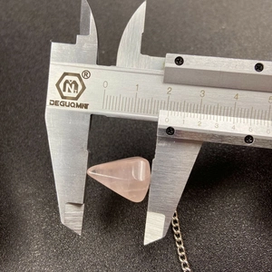 Macro view measuring the 15mm base of the rose quartz hexagonal pendulum with a caliper