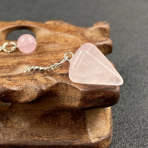 Macro shot of faceted pink quartz pendant with natural crystal texture and silver chain