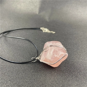 Detailed close-up of handmade wire-wrapped raw rose quartz crystal pendant with black cord