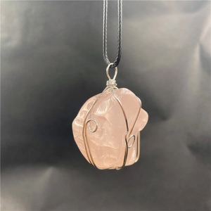 Macro detail of rose quartz raw stone pendant wrapped in silver wire with black cord