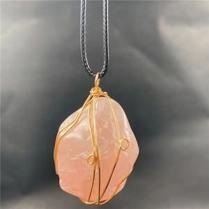 Macro detail of natural rose quartz pendant with gold wire-wrapped artisan craftsmanship
