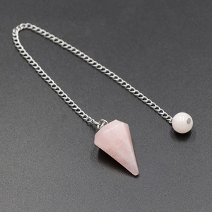 Hexagonal rose quartz pendulum with silver chain on black surface for meditation