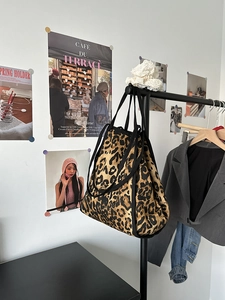Detailed shot of leopard print canvas tote bag on a rack with black trim and wide straps