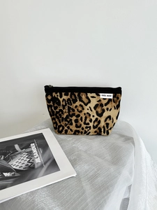 Dettaglio della borsa per cosmetici leopardata con cerniera nera ed etichetta di marca