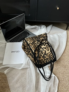 Close-up of leopard print canvas tote bag with black straps in a minimalist lifestyle setting