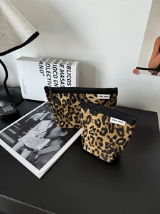 Dettaglio macro di pochette per trucchi leopardate in tela con cerniere e etichetta