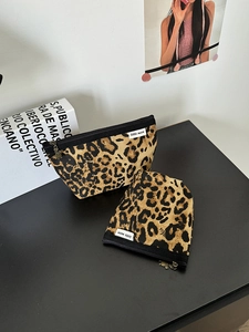 Dettaglio di borse per trucco in tela leopardata con cerniere ed etichette tessute