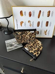 Dettaglio delle borse da trucco in tela leopardata con etichette e cerniere metalliche